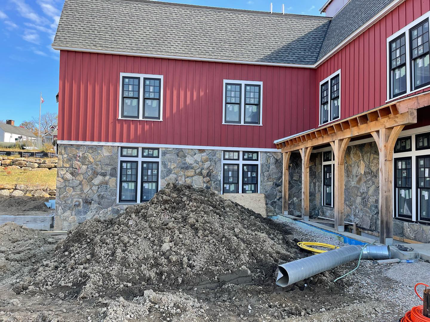 Red barn commercial building with fieldstone veneer foundation and timber frame entry porch under construction