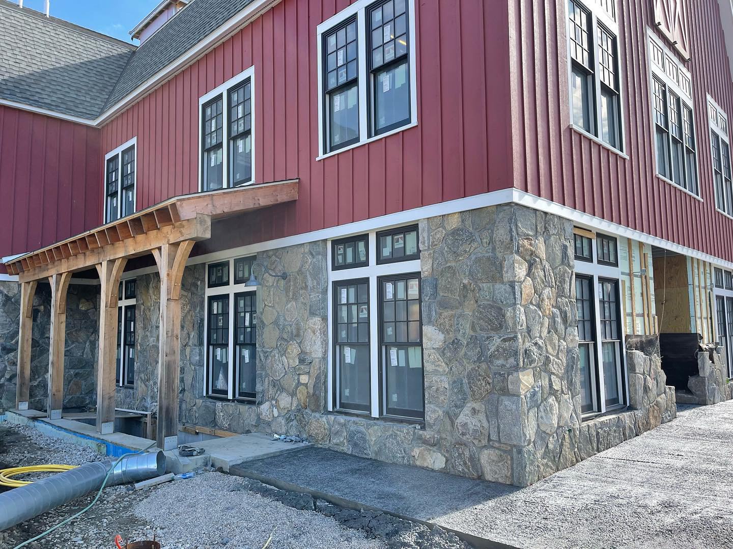 Red barn commercial building corner with fieldstone veneer, timber post porch, and black-framed windows
