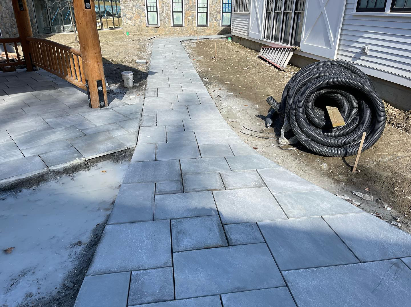 Bluestone paver walkway under construction between timber-frame lodge and garage
