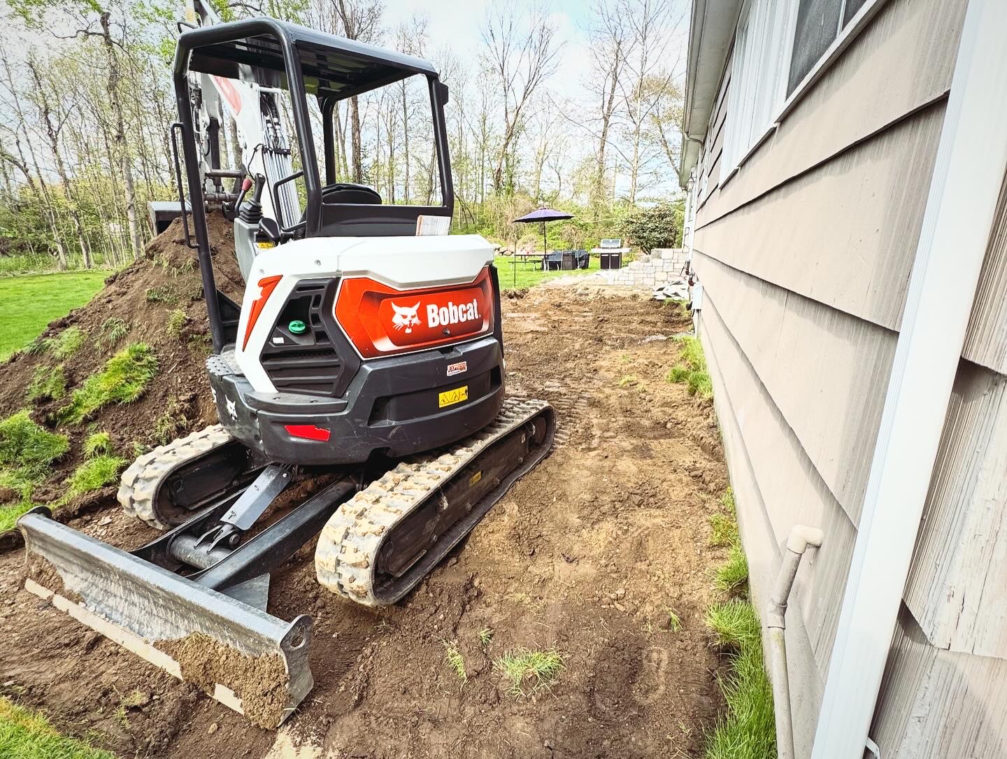 Bobcat mini excavator grading and excavating for patio installation at a residential property