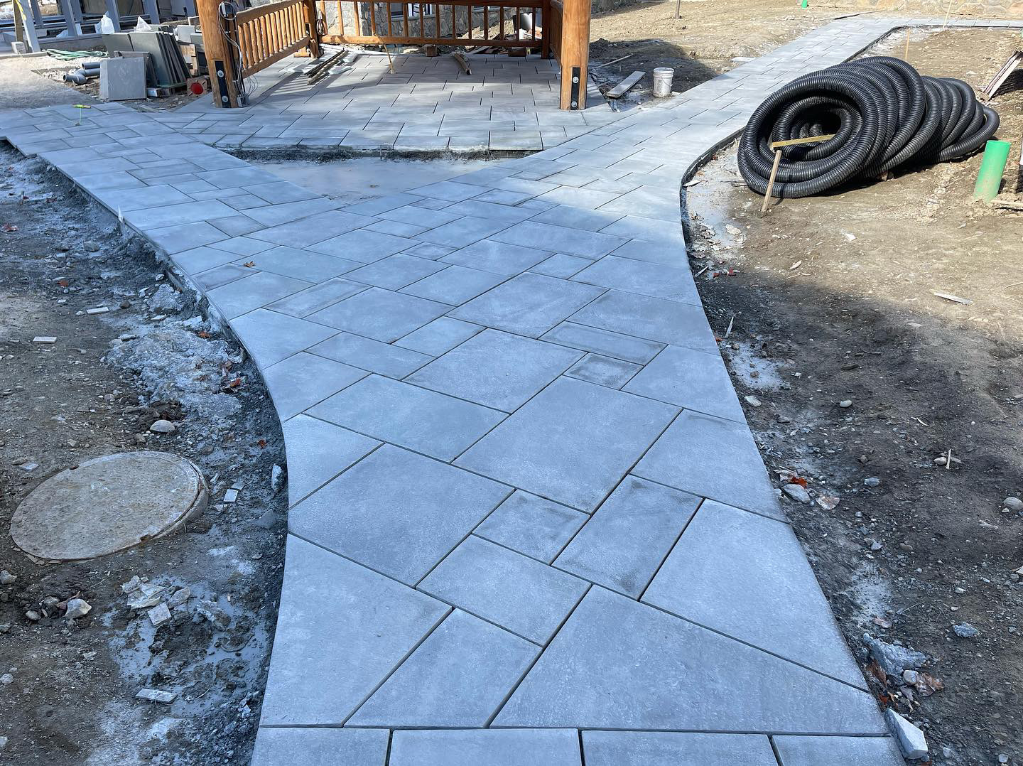 Curved paver walkway with herringbone pattern leading to timber frame porch at estate property
