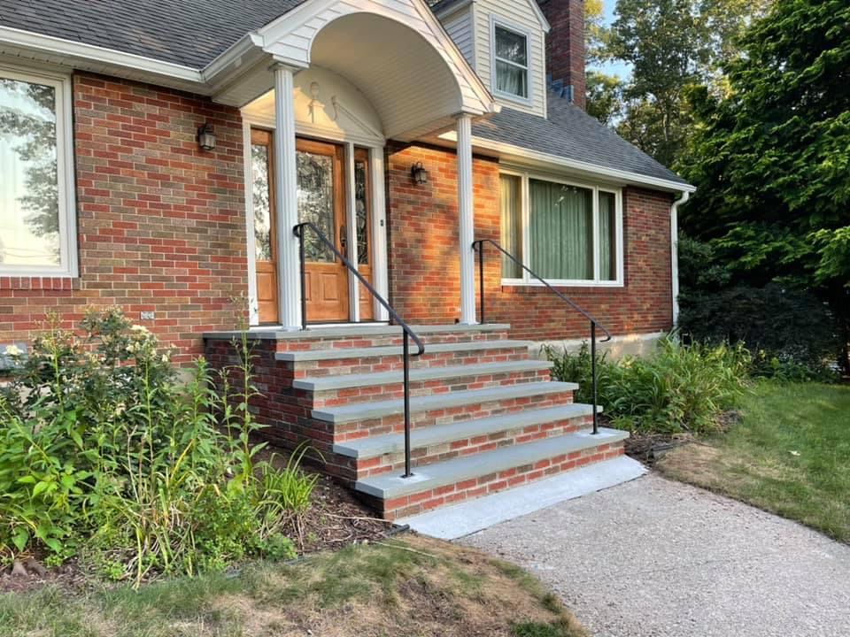 Restored brick front steps with bluestone treads, wrought iron handrails, and arched portico on colonial brick home
