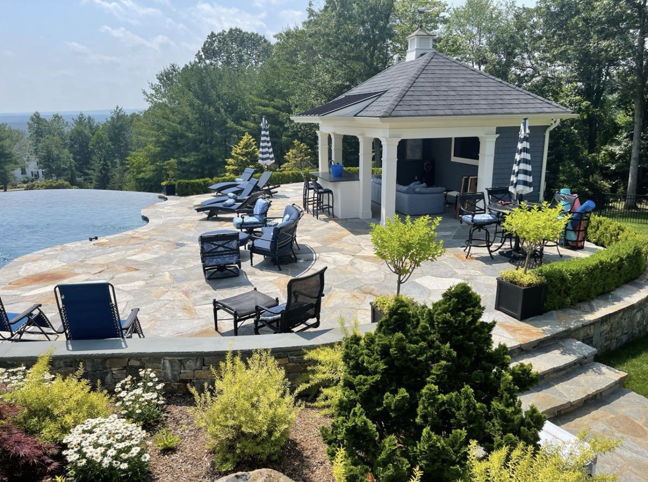 Infinity edge pool with flagstone patio, cabana, and panoramic hilltop views