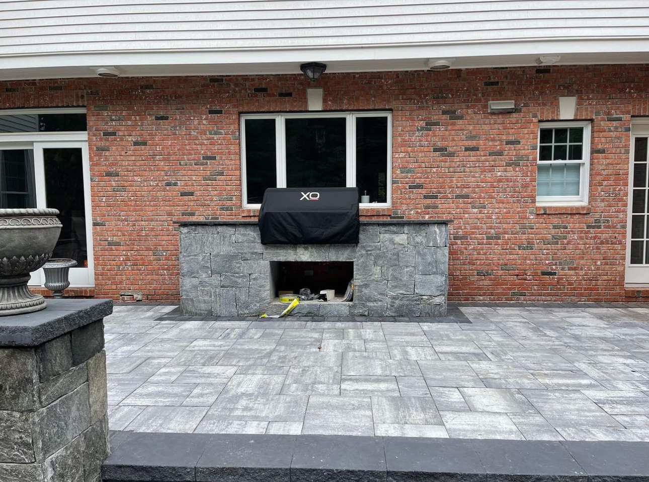Outdoor kitchen with stone veneer grill station and paver patio at a residential property