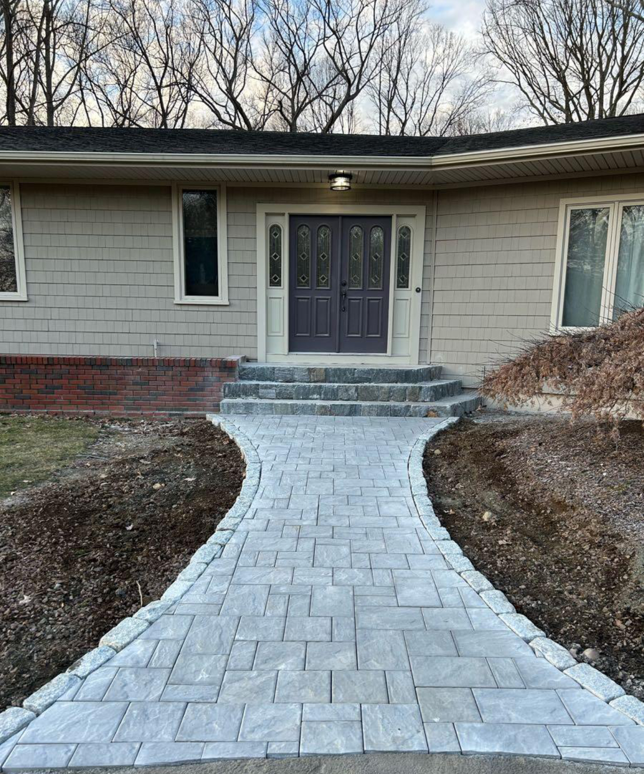 Paver walkway with stone steps leading to the front door of a residential home