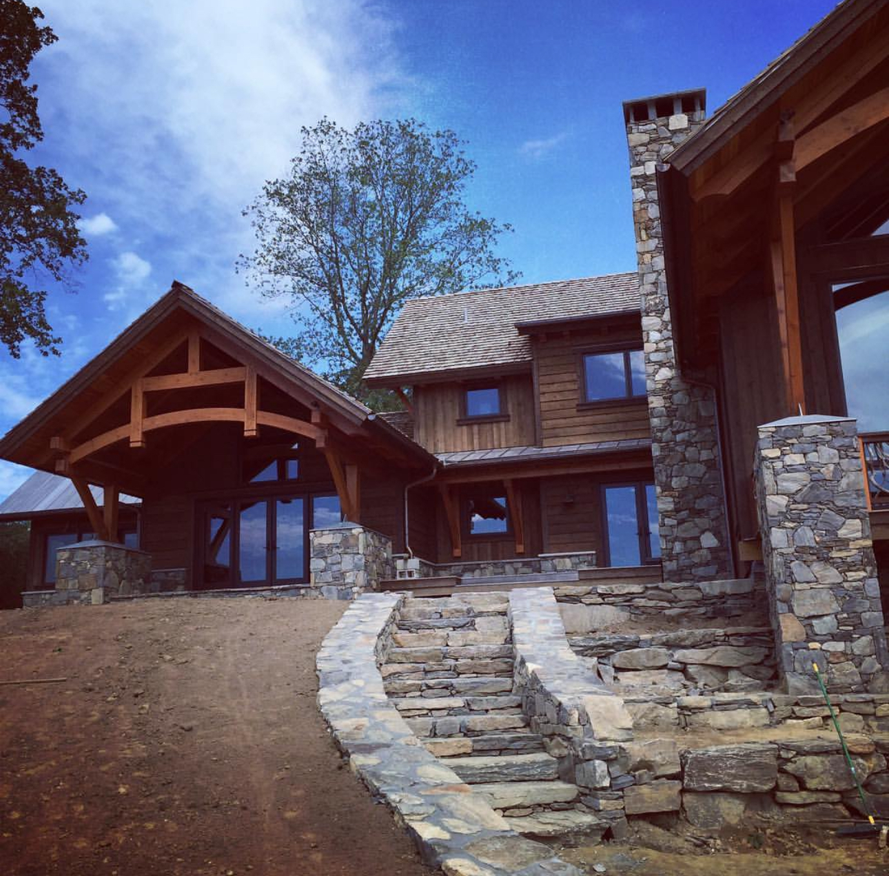 Timber frame lodge with fieldstone chimney, stone walkway, and cedar timber entry