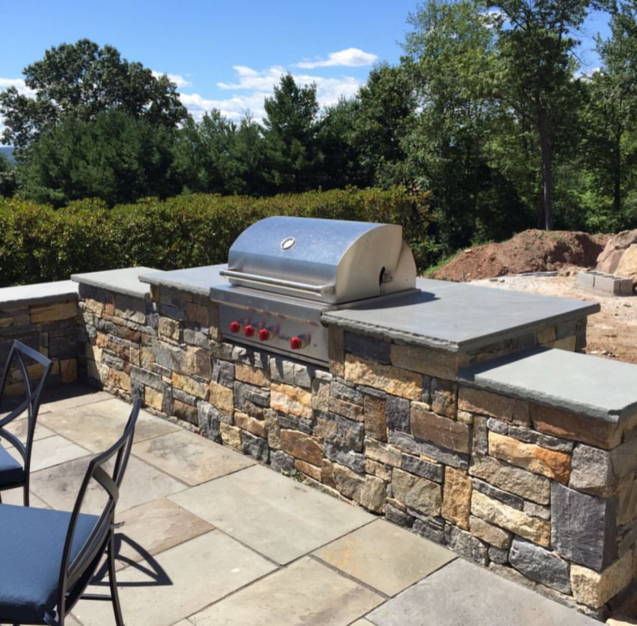 Outdoor grill station with natural stone veneer base, bluestone countertop, and built-in stainless grill